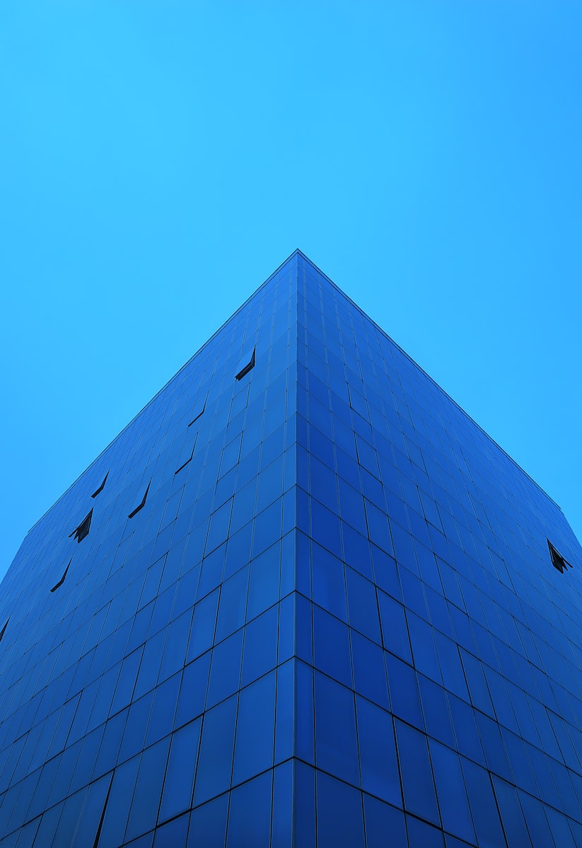 a very tall blue building with a sky background